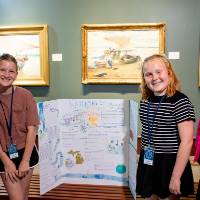 students posing with Jennifer Moss, WGVU, with their poster